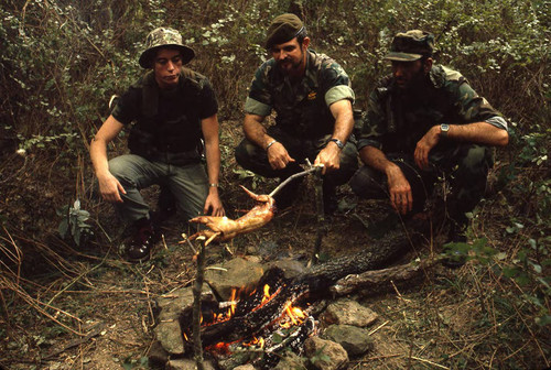 Camp instructor and survival school students cook a rabbit, Liberal, 1982