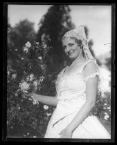 Woman in white dress and veil, posing with rose bushes