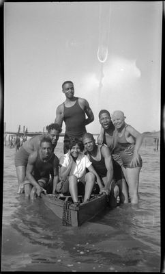 Group of men and women wading next to boat in lake