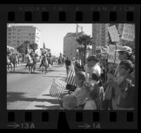 People, some with signs supporting President Richard Nixon, watching Veterans Day parade in Long Beach, Calif., 1969