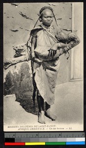 Woman carrying child and wood, German East Africa, ca.1920-1940