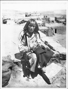 Hopi Indian man darning a garment, ca.1900