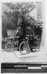 Fr. J. E. Morris, MM, and a Japanese man stand with bicycles in front of a tree, Kyoto, Japan, ca. 1938
