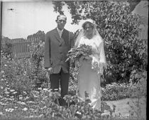 Bride and groom posing in flower garden, c. 1912