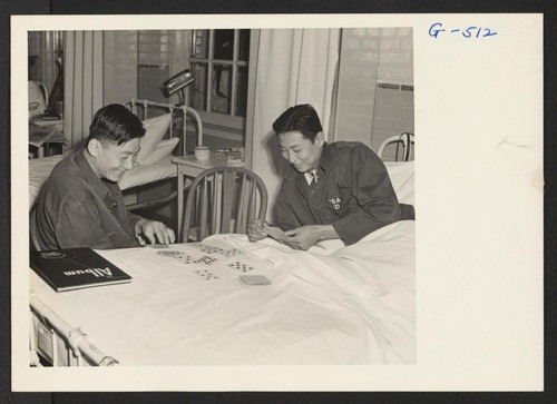 Pvts. Kazuto Yoshioka and Wallace Hisamoto have a game of cards in the ward at Walter Reed Hospital. Yoshioka lost his right arm below the elbow and Hisamoto his left leg, both in action with the 100th Battalion in Italy. Photographer: Van Tassel, Gretchen "Washington, D.C."