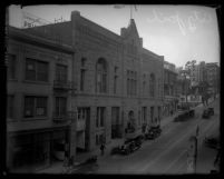 City street with pedestrians, cars and buildings including Los Angeles city jail, circa 1920