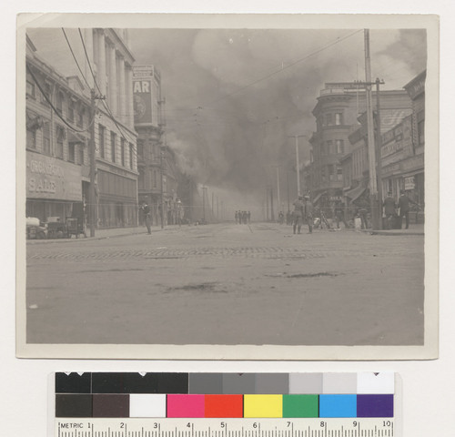 [Soldiers patroling Sixth St. From Market. Hale Bros. department store, left. Fire burning in distance.]