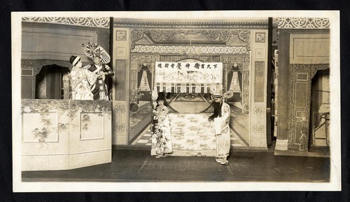 Man and a woman center stand before a bed, a man and a woman stand on a balcony /
