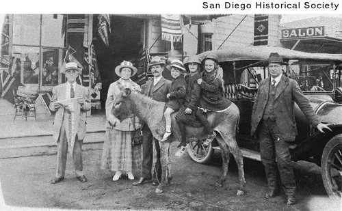 A group of tourists in Tijuana standing with three children sitting on a donkey