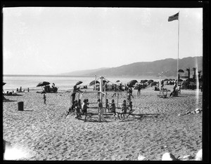 A group of children sitting on a revolving piece of playground equipment at Santa Monica beach