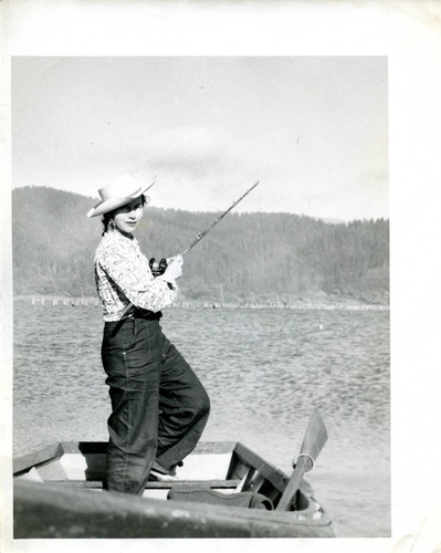 Woman fishing while standing in a dingy — Calisphere