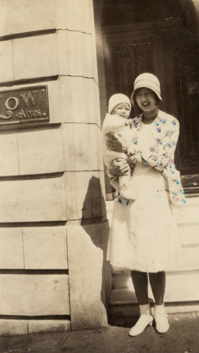 Dorothy Siu holding Rodney Low in front of a building marked Low Apartments