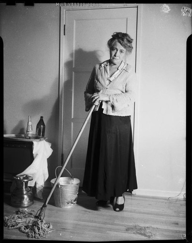 Mrs. Flournoy, in cardigan with holes, mopping floor, [1950s]
