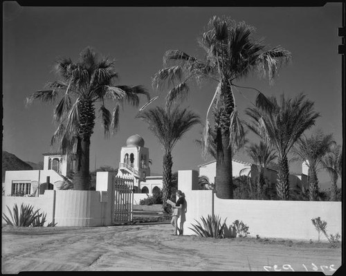 El Kantara, house with onion dome, horseshoe arches, and tiled roof, with woman at gate, Palm Springs, [1930s or 1940s?]