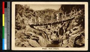 Men crossing a small wooden bridge over a river, Ethiopia, ca.1920-1940