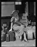 Marta Eggerth, opera singer, sits on her luggage upon arrival at the train station, Los Angeles, 1935