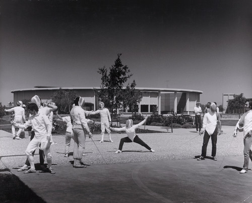 Photograph of a fencing class or club practicing in front of the Music Building at California State University, Hayward