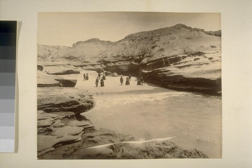 [People on small beach surrounded by dramatically eroded cliffs; La Jolla area?]