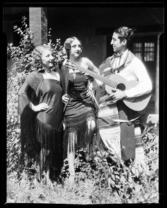 Man playing a guitar for two women