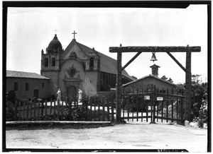 Exterior view of El Carmelo Mission (1770) at Carmel-by-the-Sea, showing the wooden gate in the foreground, June, 1926