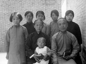 Den flok der blev døbt pinsedag fra udstationen Shaotsiho Hr. Liu sidder til højre med bibelen i sin hånd ved siden af sin hustru og lille søn