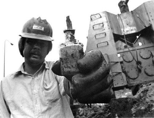 [Worker at construction site of Embarcadero Center holding a bottle dug up at the site]
