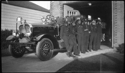 Six firemen leaning against Oakland Fire Department fire truck