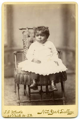 Portrait of girl in white dress seated on chair