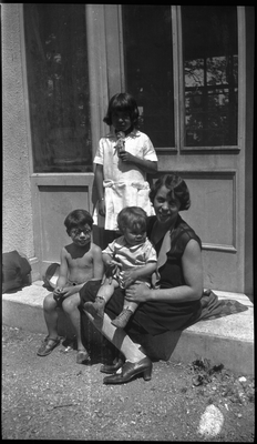 Woman and three children sitting in doorway of building