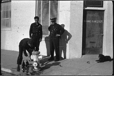 Firemen attaching fire hose to hydrant in front of Gleason and Company building