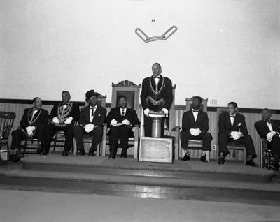 Al Fulcher speaking at podium with masons seated on stage