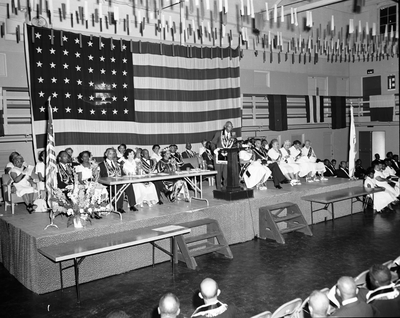 Masons and members of the Order of the Eastern Star seated on stage in front of U.S. flag