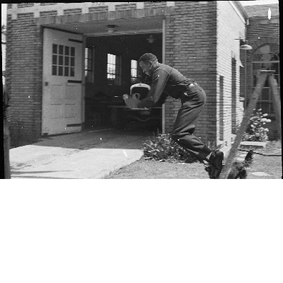 Fireman jumping off ladder in front of Oakland Fire Department fire engine no. 22