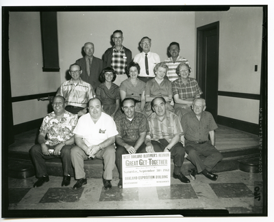 Group photograph of men and women in front of sign for West Oakland Oldtimers Reunion