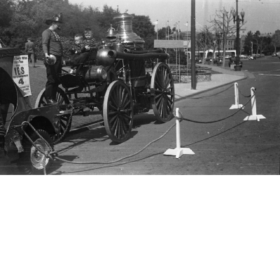 Oakland firefighter dressed in historical costume and two boys riding antique fire truck