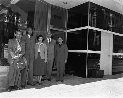 Four men and a woman standing in front of Trans-Bay Federal Savings and Loan Bank building