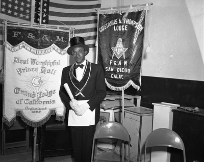 Al Fulcher wearing mason regalia standing next to Gustavus A. Thompson Lodge banner