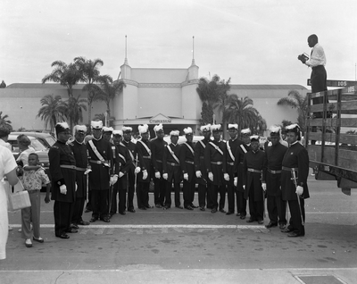 Group of men in masonic knights templar uniforms standing in parking lot in front of gymnasium