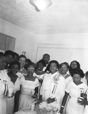 Group of women in white gowns and conference ribbons standing next to punch table