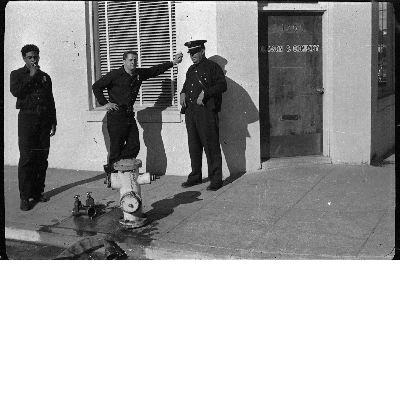 Firemen attaching fire hose to hydrant in front of Gleason and Company building