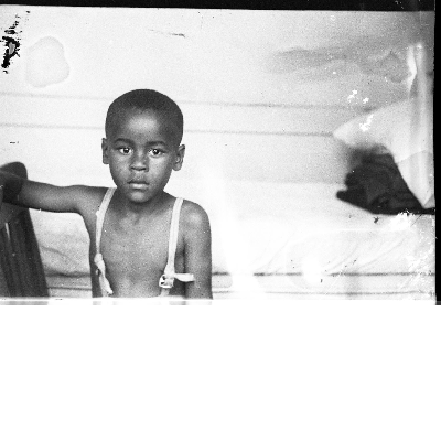 Boy in overalls sitting in chair