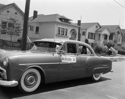 Car parked on street with banner, "Menelik No. 36"