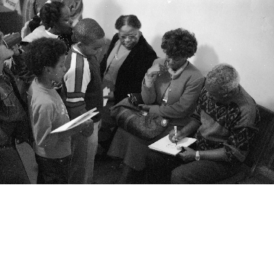 Group of children and women watching Morrie Turner draw cartoon