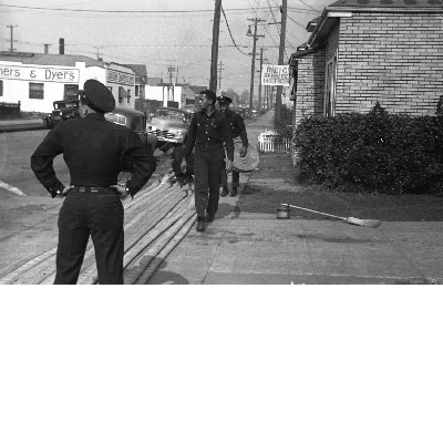 Firefighters rolling up fire houses on sidewalk