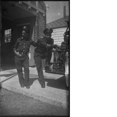 Two Oakland firemen standing next to fire truck