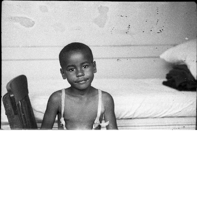 Boy in overalls sitting in chair