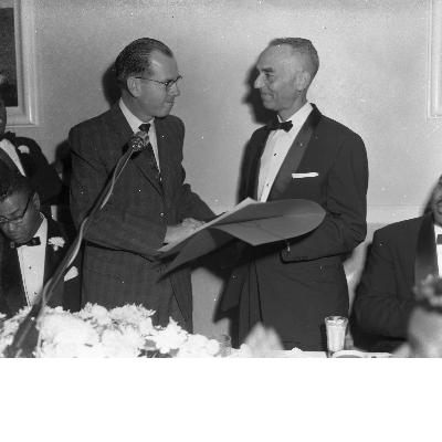 Al Fulcher and man shaking hands in front of microphone