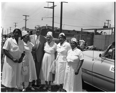 Four women wearing Menelik fez caps standing next to Oakland Mayor Clifford Rishell