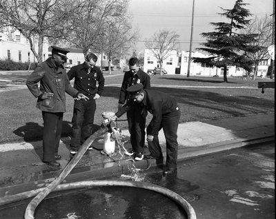 Four firemen attaching hose to fire hydrant