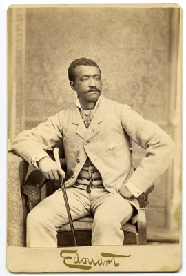 Portrait of man seated holding cane